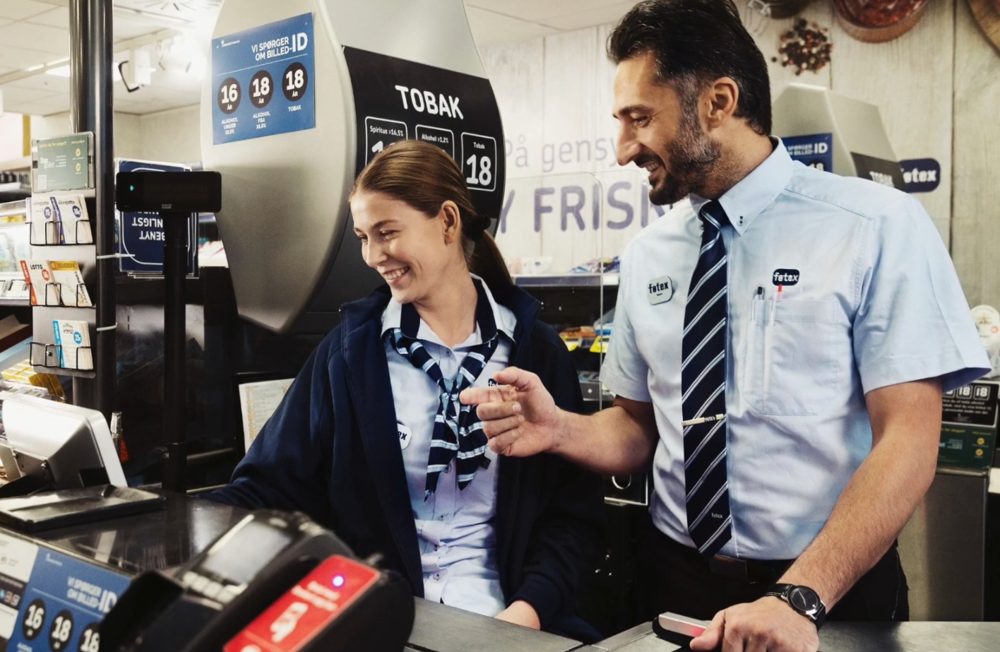 Smilende kvinde og mand der arbejder i kassen i Føtex